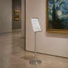 Displayhouder in geborsteld roestvrij staal in een museum naast een werk van Van Gogh